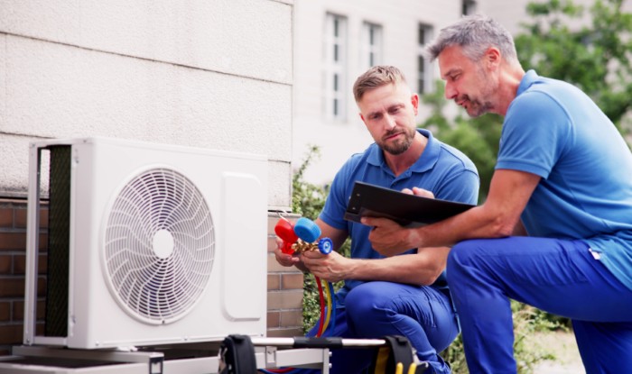 HVAC technicians installing an outdoor air conditioning unit in Erie
